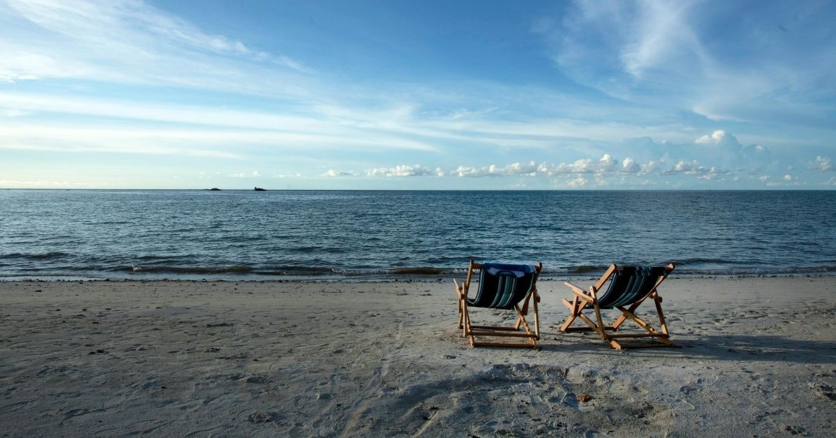 duas cadeiras de praia em frente ao mar